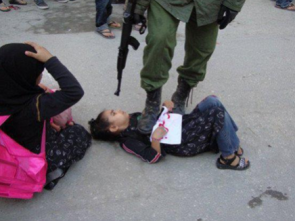 soldat israélien pointant son arme sur une jeune fille à terre